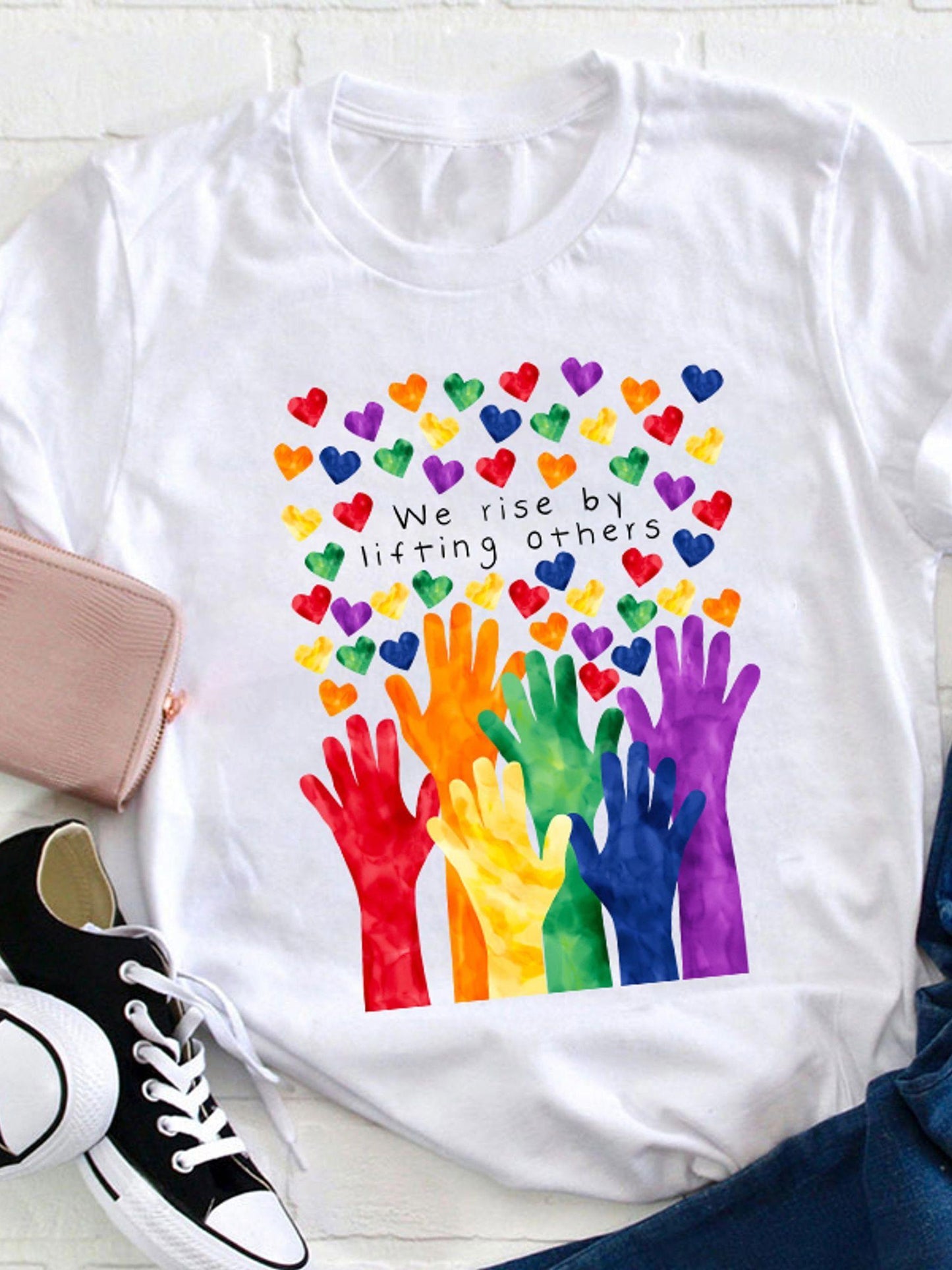 Women's Graphic T-Shirt We Rise By Lifting Others Colorful Hearts And Rainbow Hands