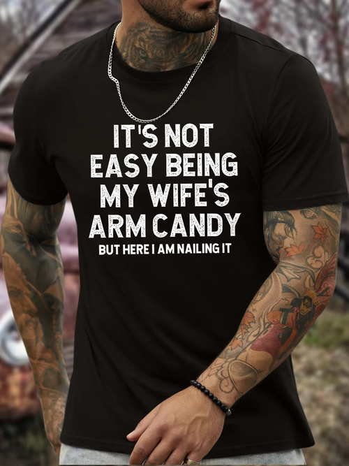 Men's Graphic T-Shirt Its Not Easy Being My Wifes Arm Candy Here I Am Nailing It Bold White Lettering On Solid Black Cotton Shirt